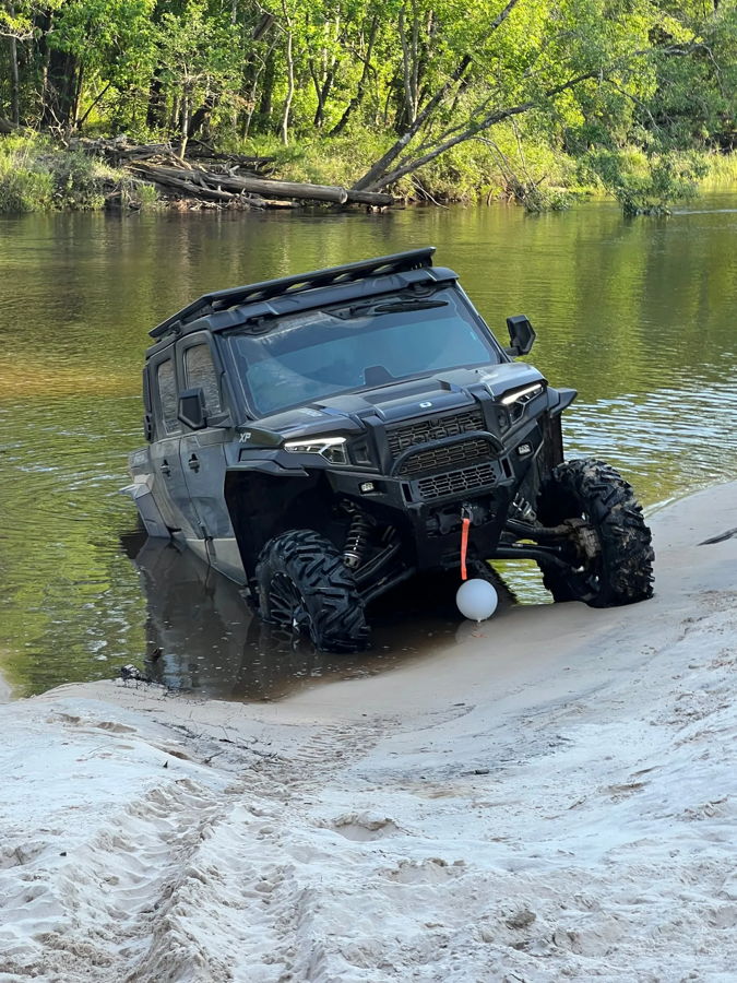 Polaris Xpedition XP5 tilted riverbank sandy shore partially submerged tires wooded river Shane's Compact Electric horn gallery photo 4