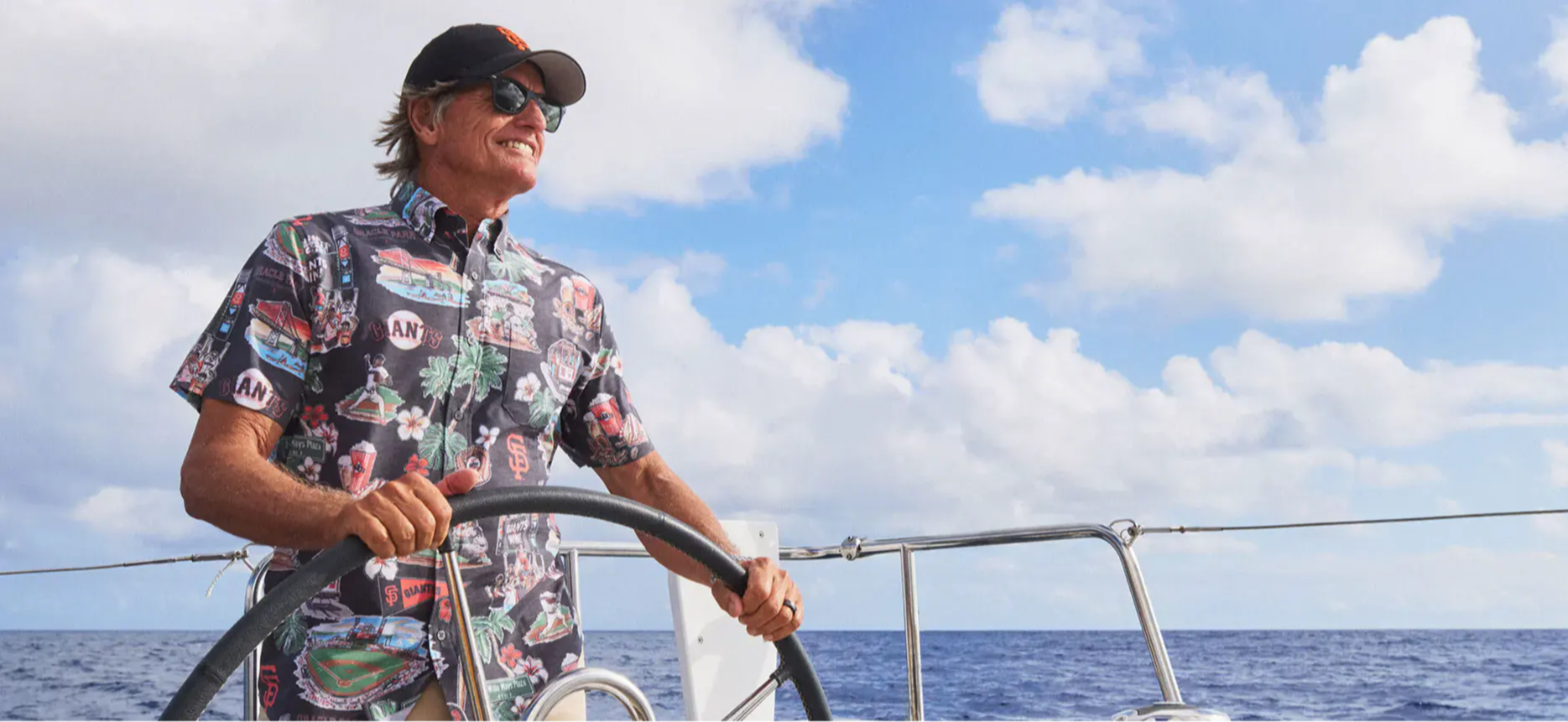 A person steering a boat on the ocean under a cloudy sky.