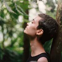 A close up of a woman leaning against a tree