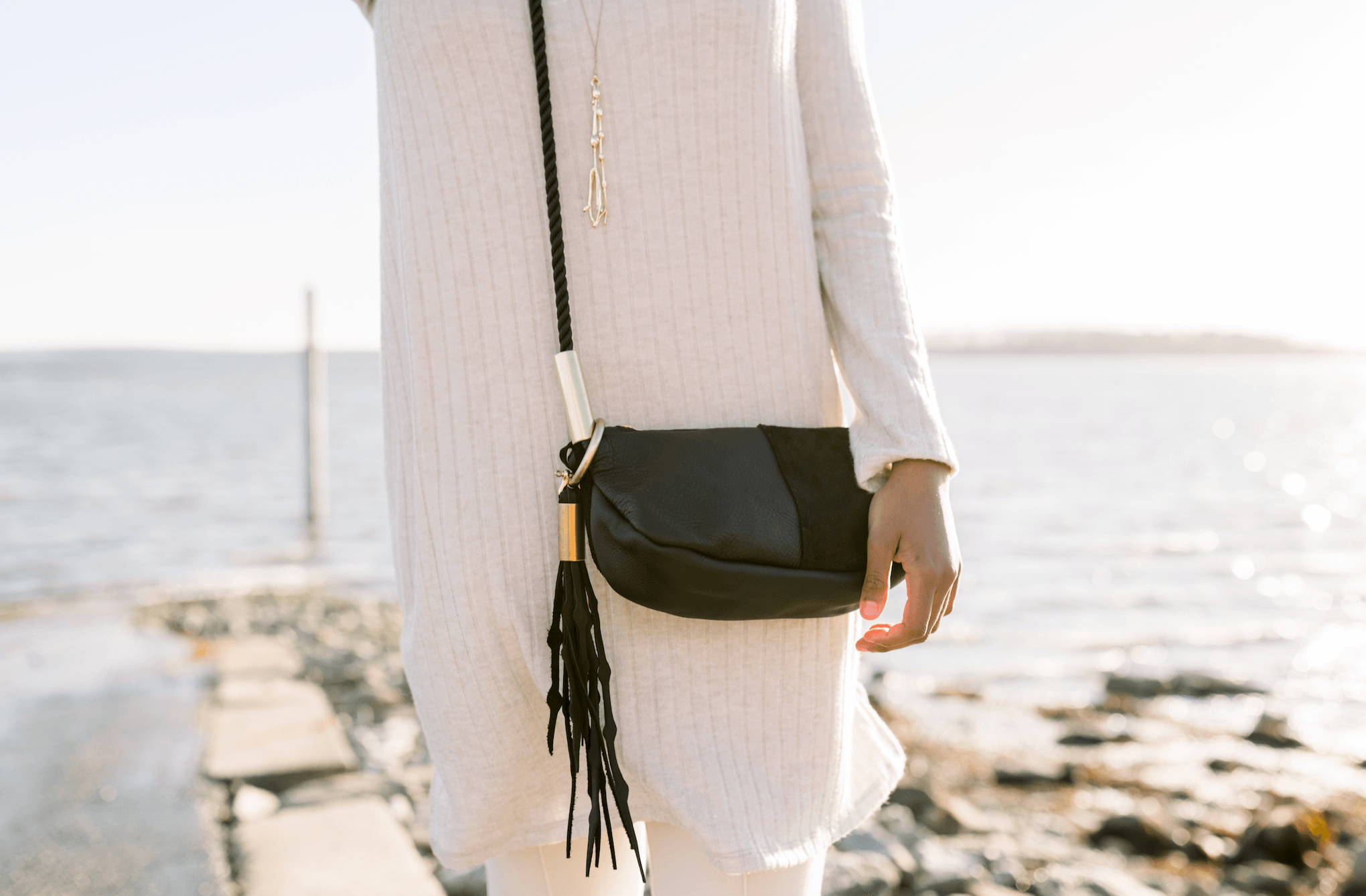Woman wearing black leather zip crossbody with seaweed tassel