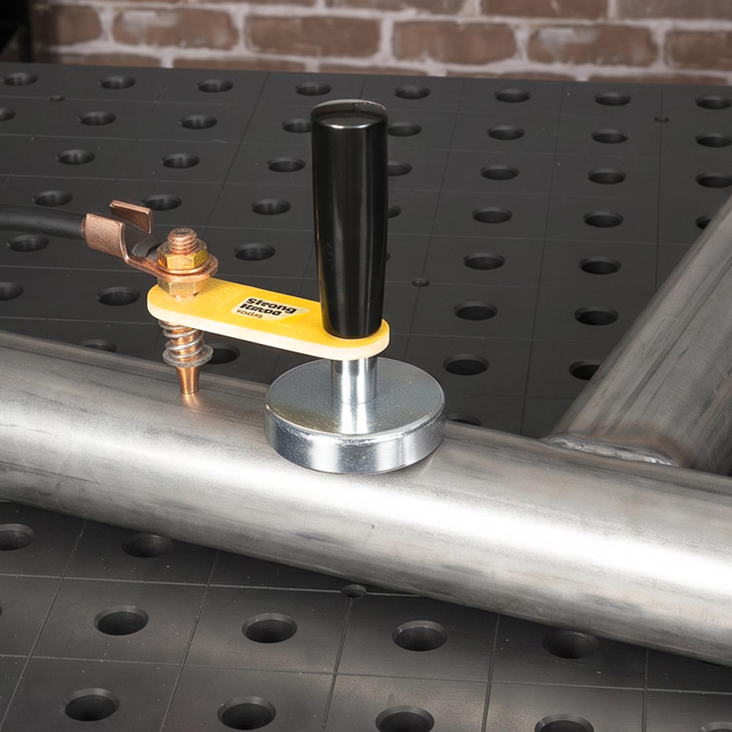 Welding tool clamped to a metal pipe on a work surface.