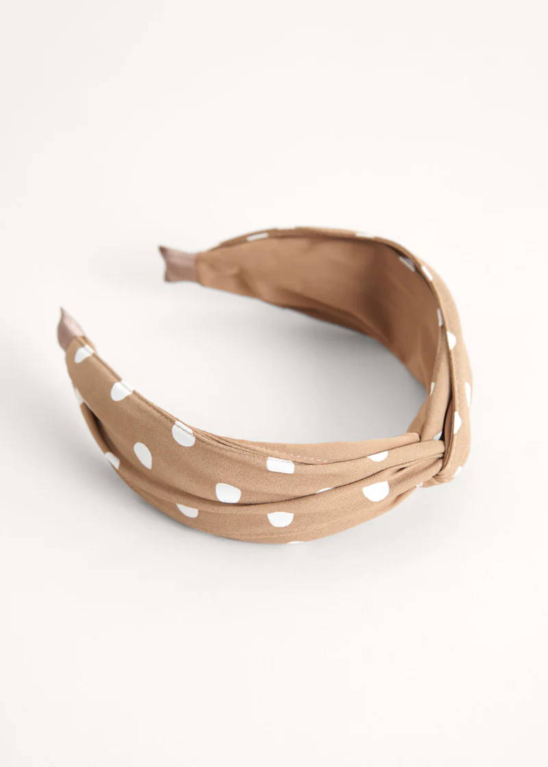 A headband in beige tones with white polka dots