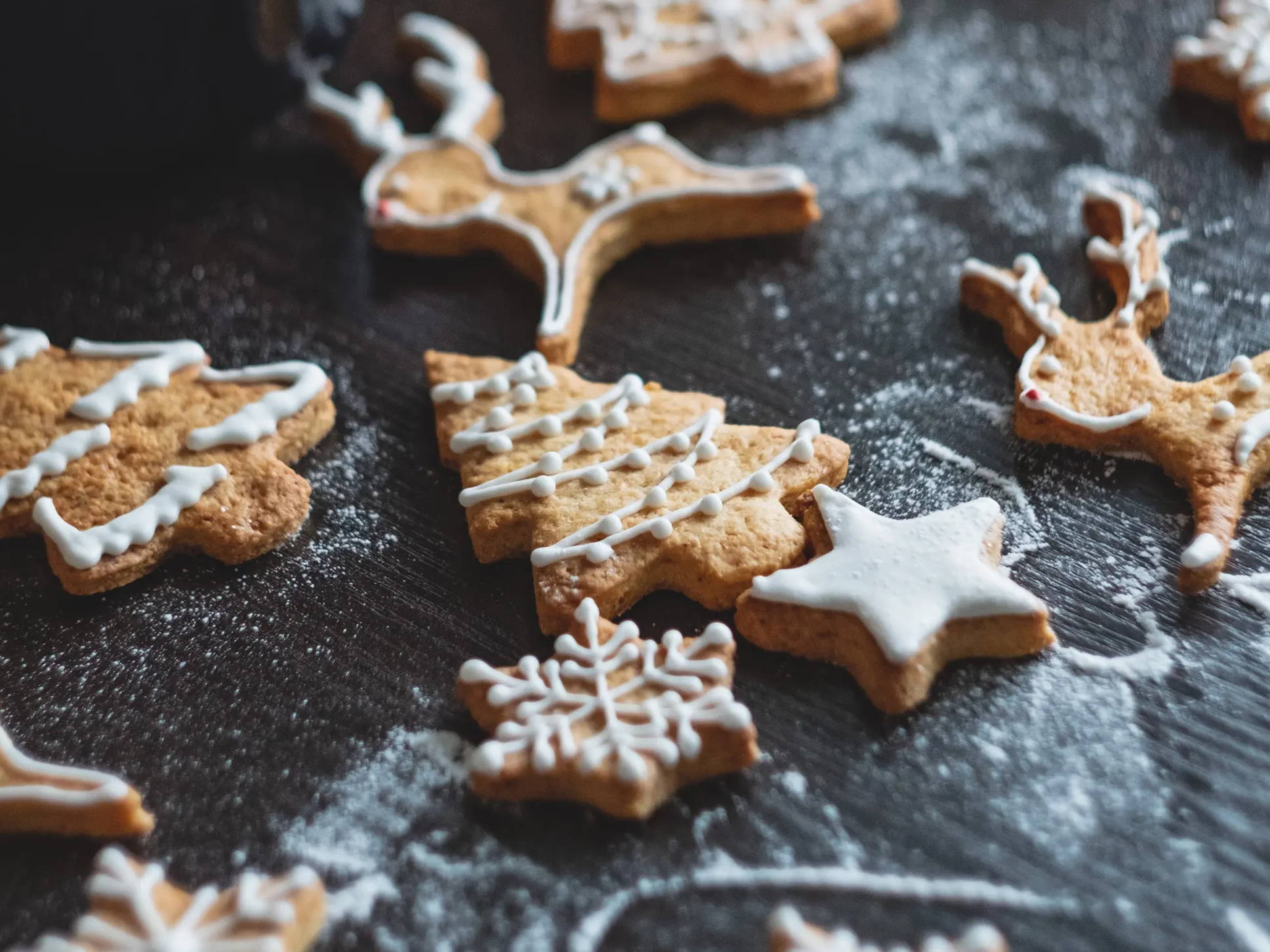 Iced and decorated gingerbread cookies on a counter dusted with flour.