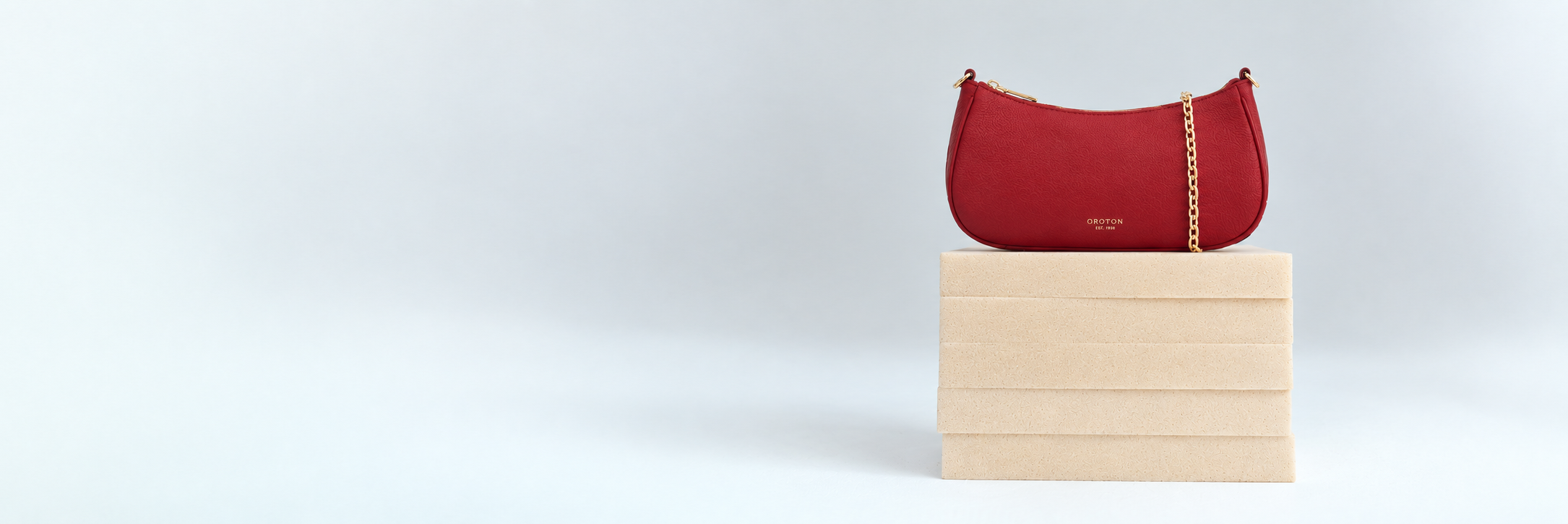 Red handbag on a wooden block against a light background.