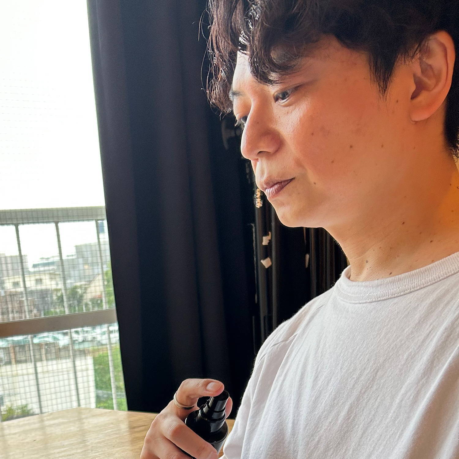 A person in a white shirt holding a device, looking thoughtfully.