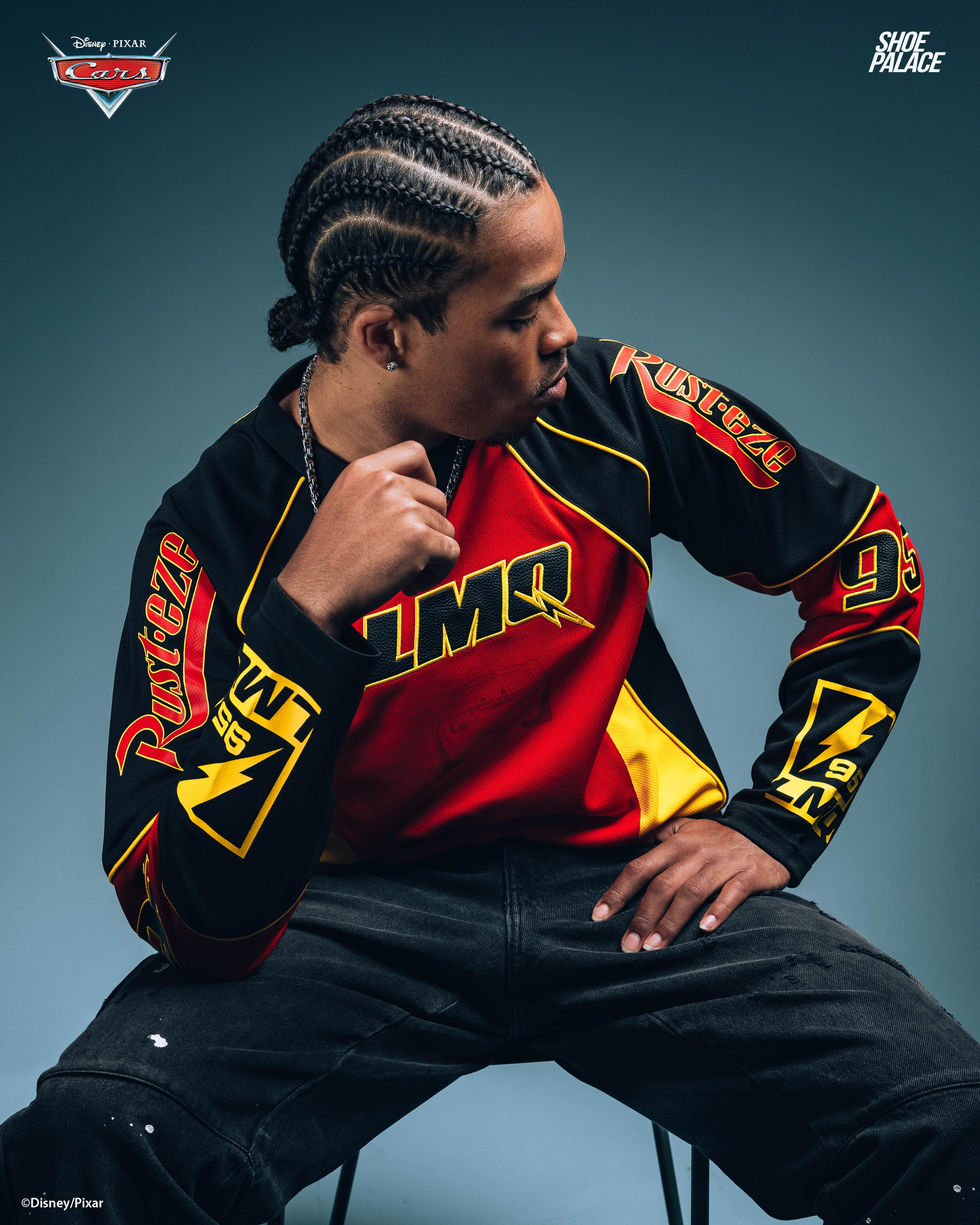 Young man with braided hair wearing a colorful athletic shirt, seated in profile.