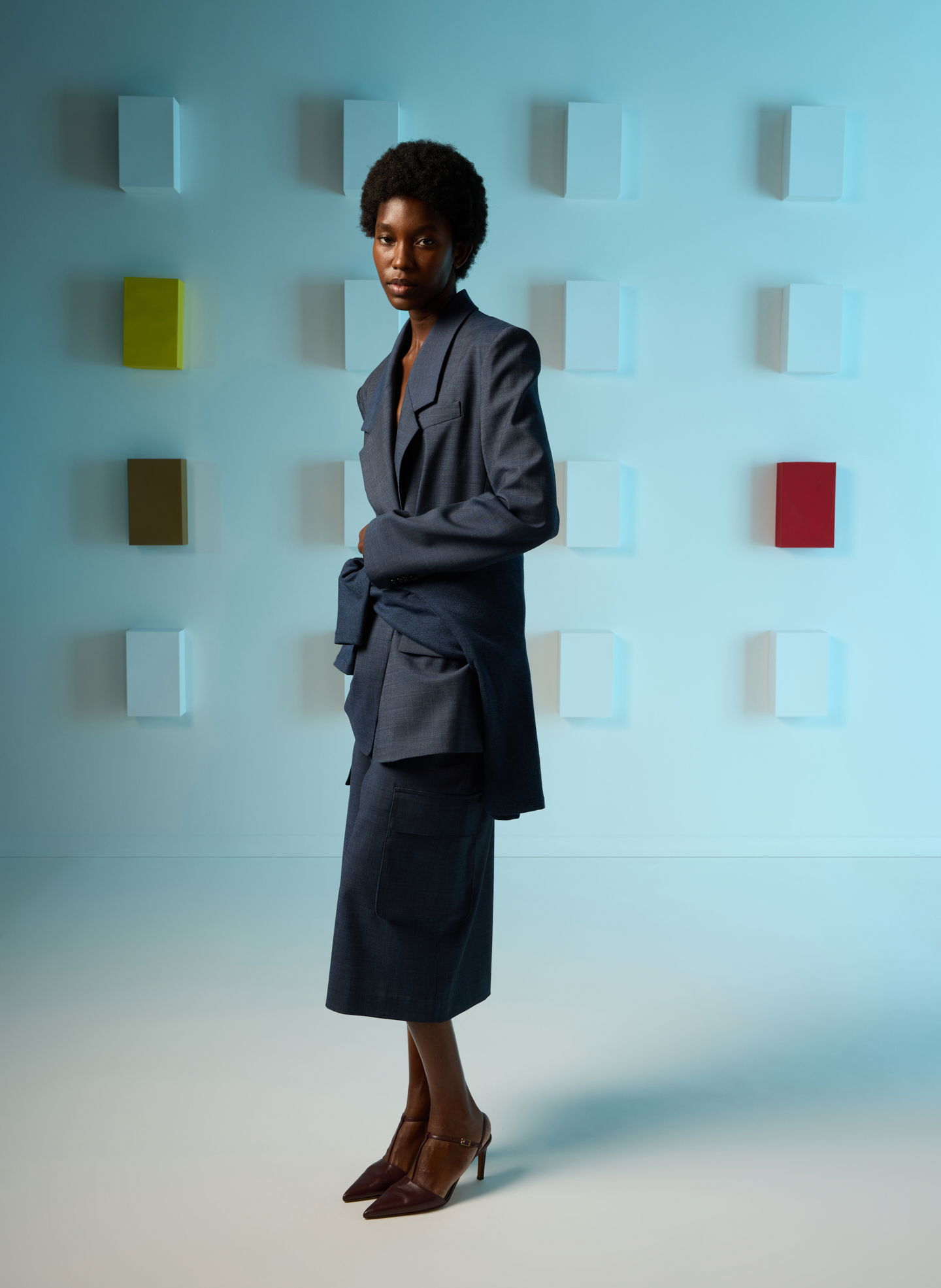 Model in a tailored blue suit against a colorful abstract background.