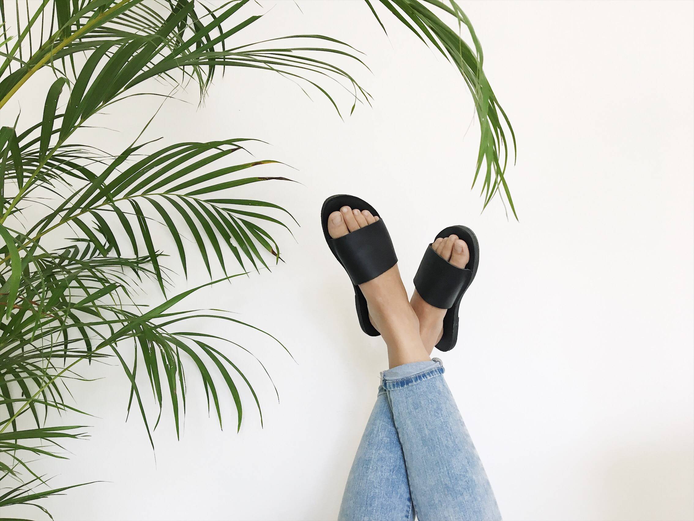 Two feet in the air wearing women's upcycled leather sandals by Brave Soles.