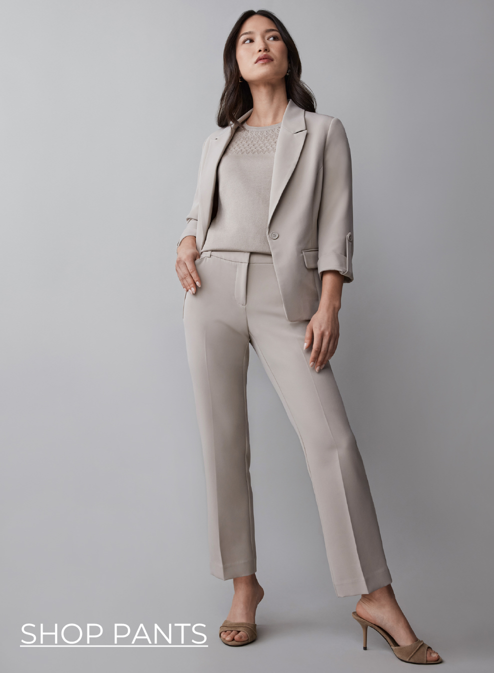 Woman in a light suit posing against a gray background.