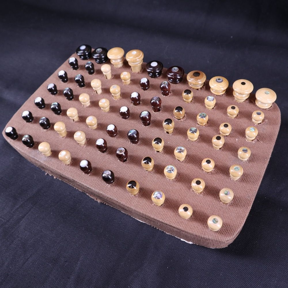 A wooden board with variously sized beads arranged in rows.