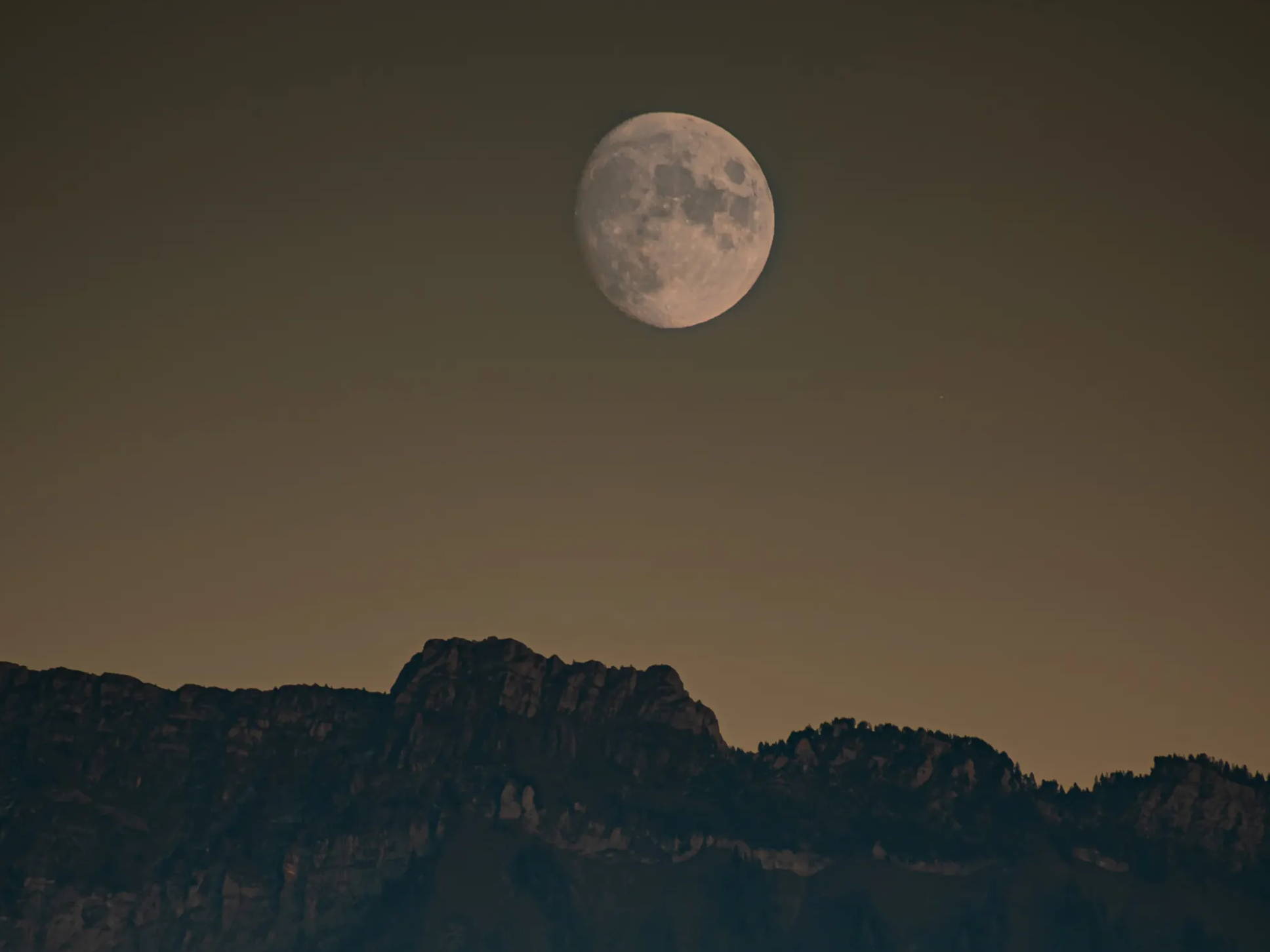 Full moon above a mountain range