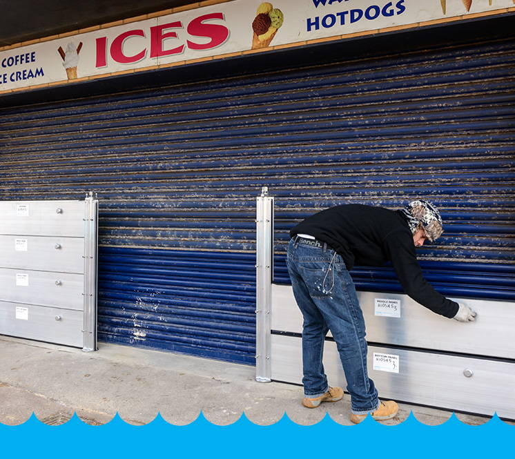 A person attaching a WaterWall by Caro Flood Defence to a business to ensure it does not flood. 
