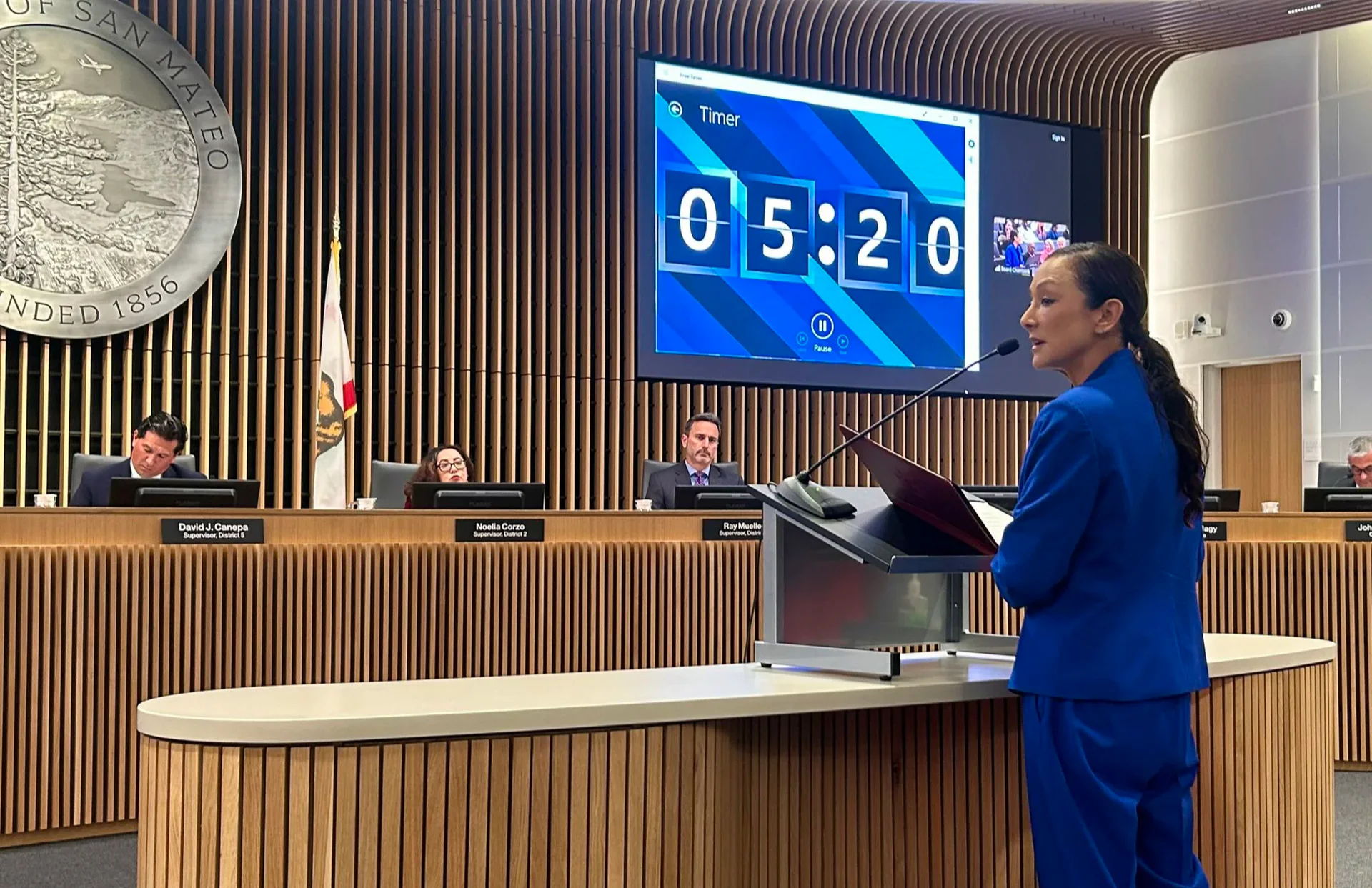 Person speaking at a podium with a timer in a meeting room.