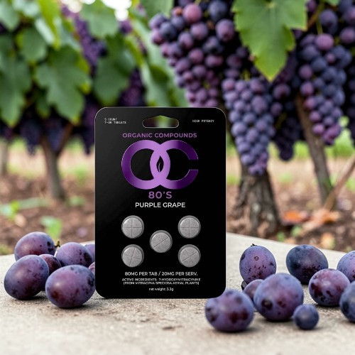 Grapes and a packaging of purple grape-flavored candy on a surface.