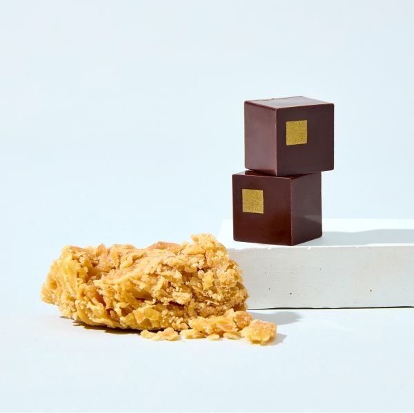 Chocolate cubes beside a crumbly texture on a light background.