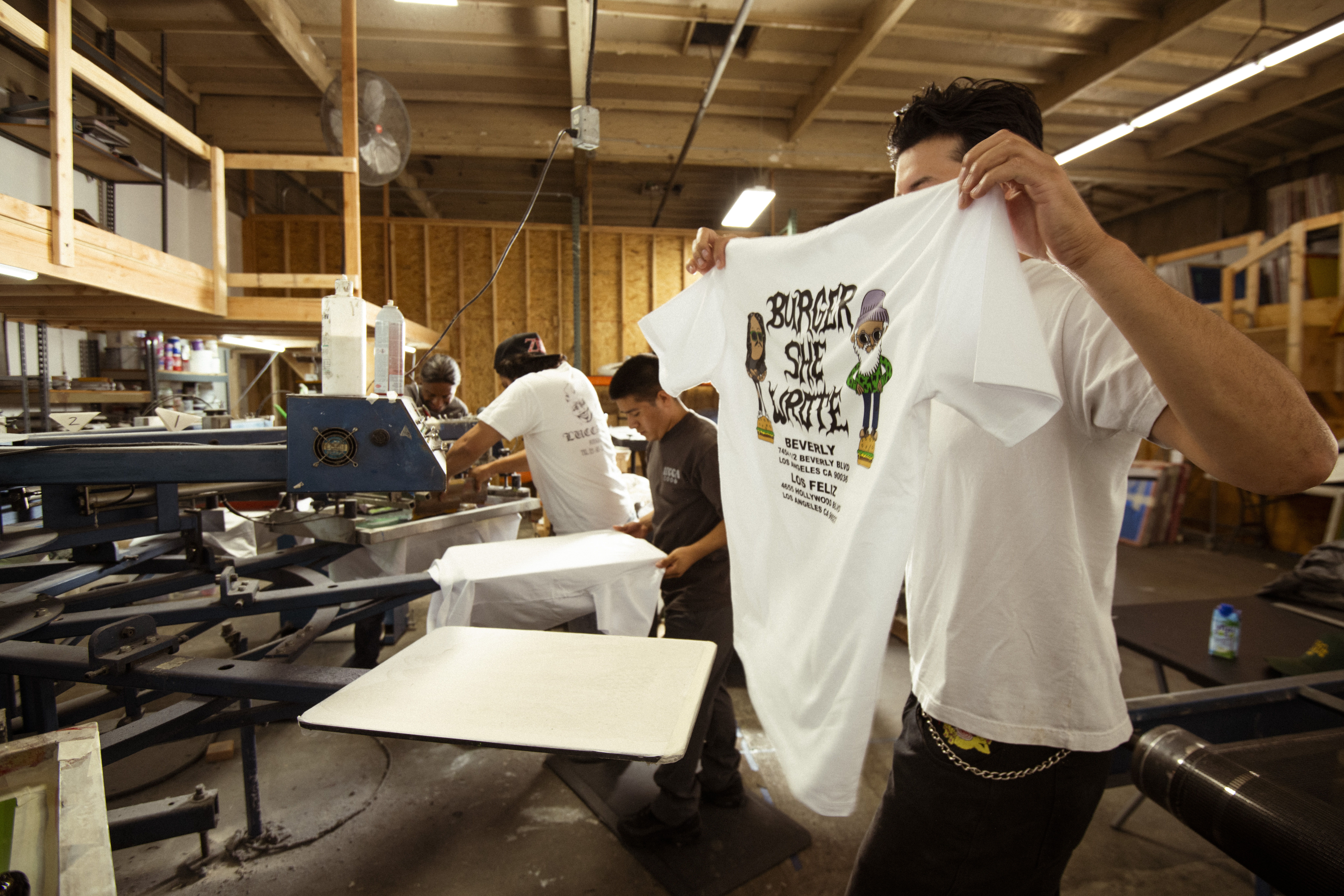 Workers printing t-shirts in a workshop setting.
