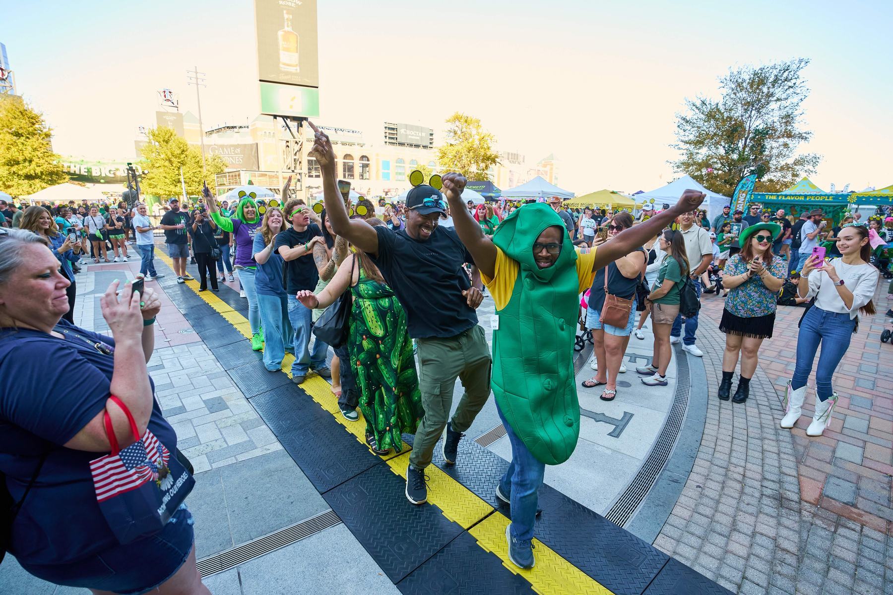 Guest in pickle costume leading a conga line through the crowd at The Big Dill at Texas Live Arlington Texas 2025.