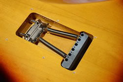 Close-up of an electric guitar bridge and tremolo system.