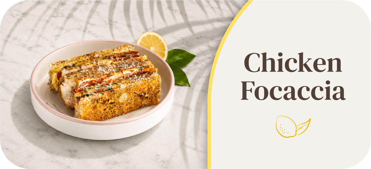 A plate of chicken focaccia with lemon slice and herbs.