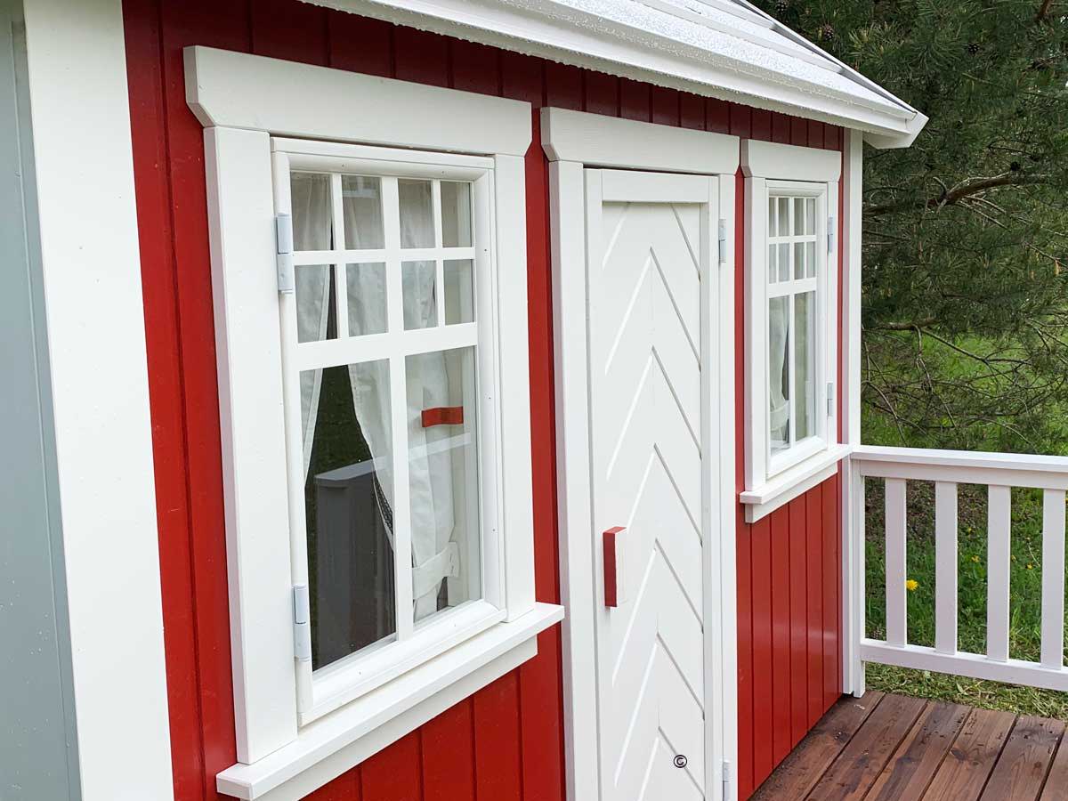 White wooden door on a red wooden playhouse by WholeWoodPlayhouses