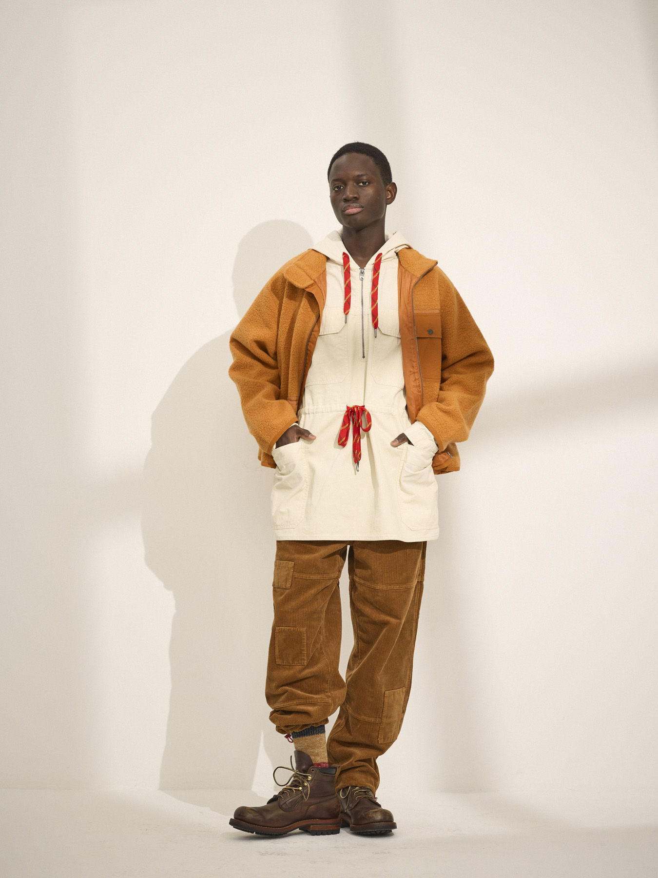 Person wearing a cream and orange outfit against a plain background.