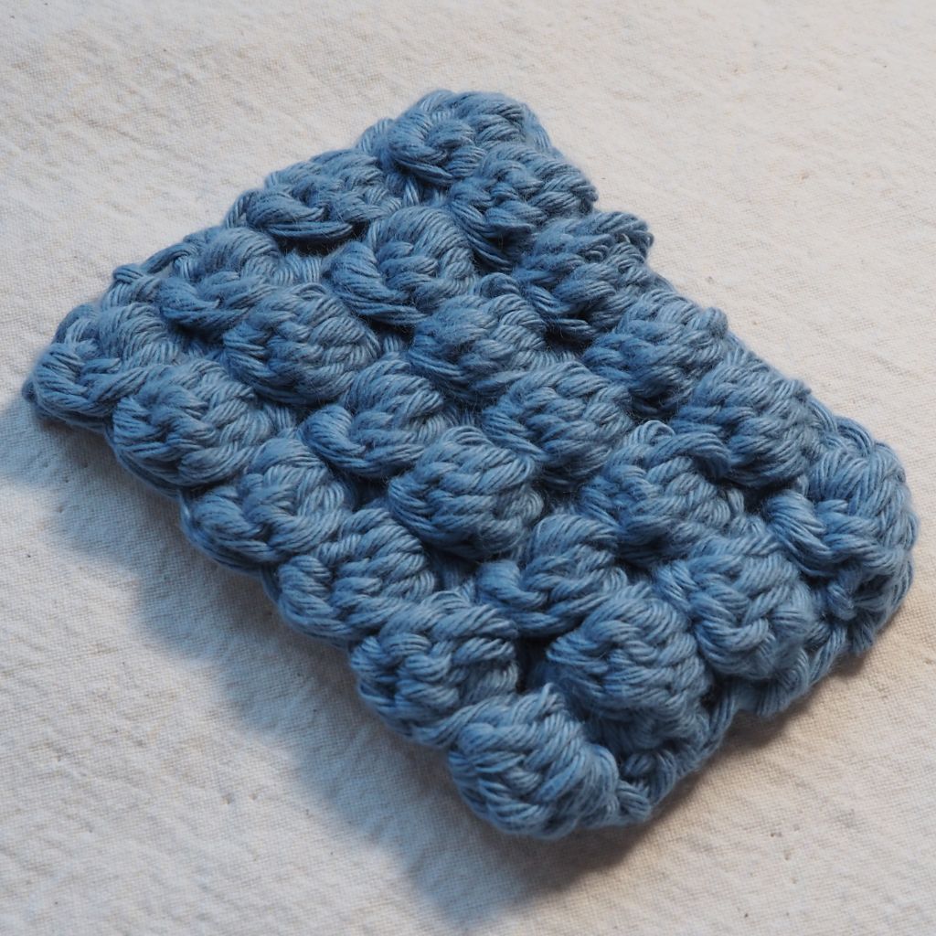 Maschenprobe aus blauem Garn, die das Noppenmuster zeigt.