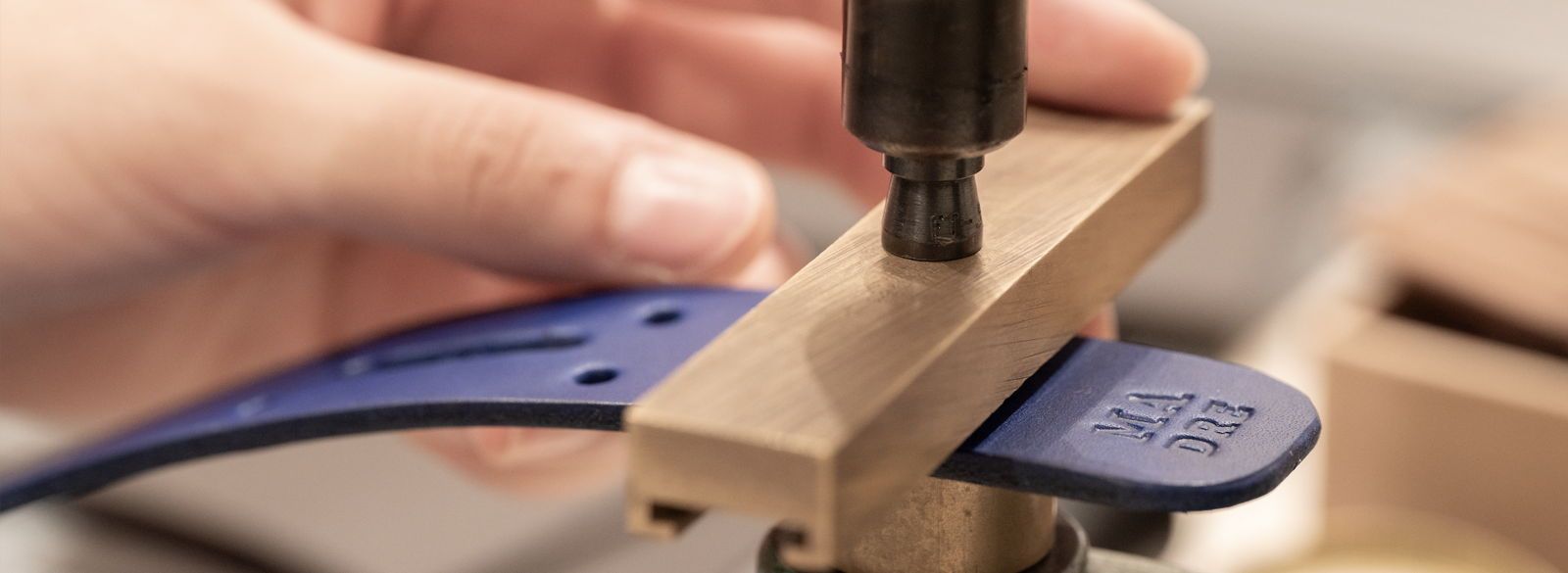 An artisan pressing a personal detail into blue leather at Atelier Madre