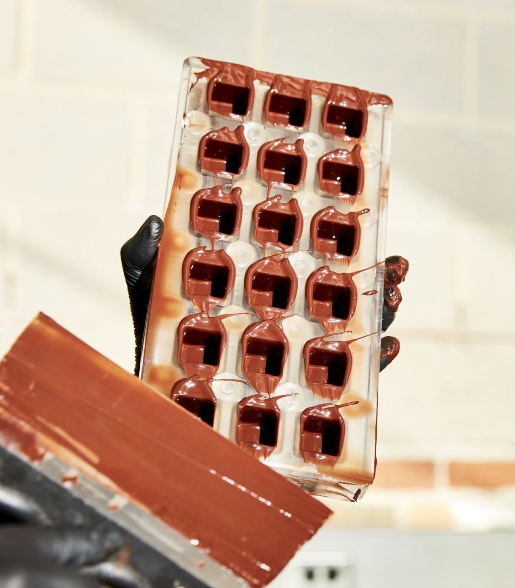 A person holding a chocolate mold with several cavities.