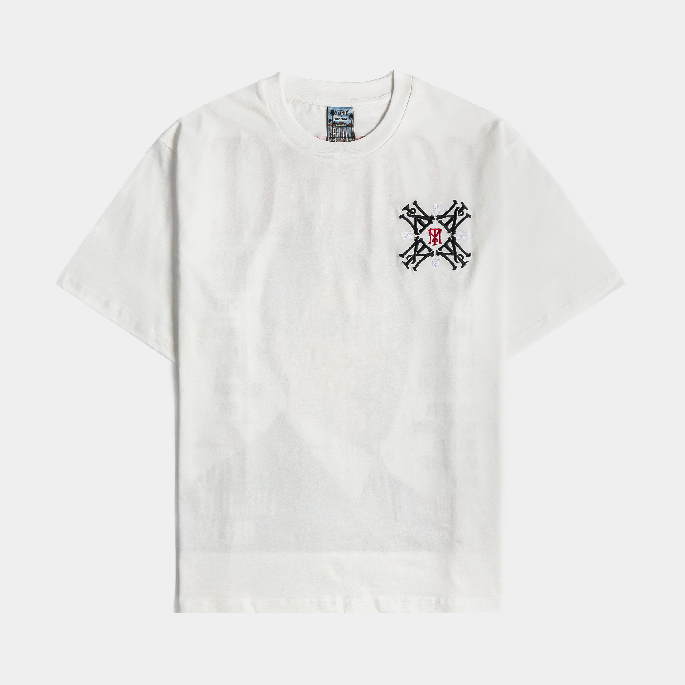 White t-shirt with a black and red embroidered design on the chest.