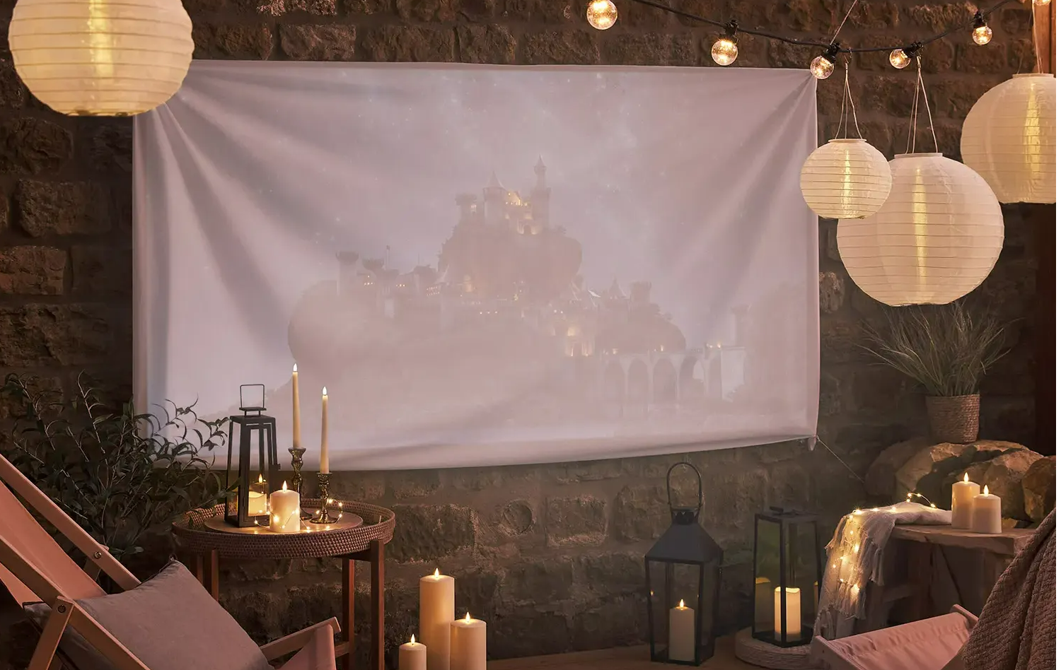 An outdoor movie night setting with hanging solar lanterns and festoon lights.