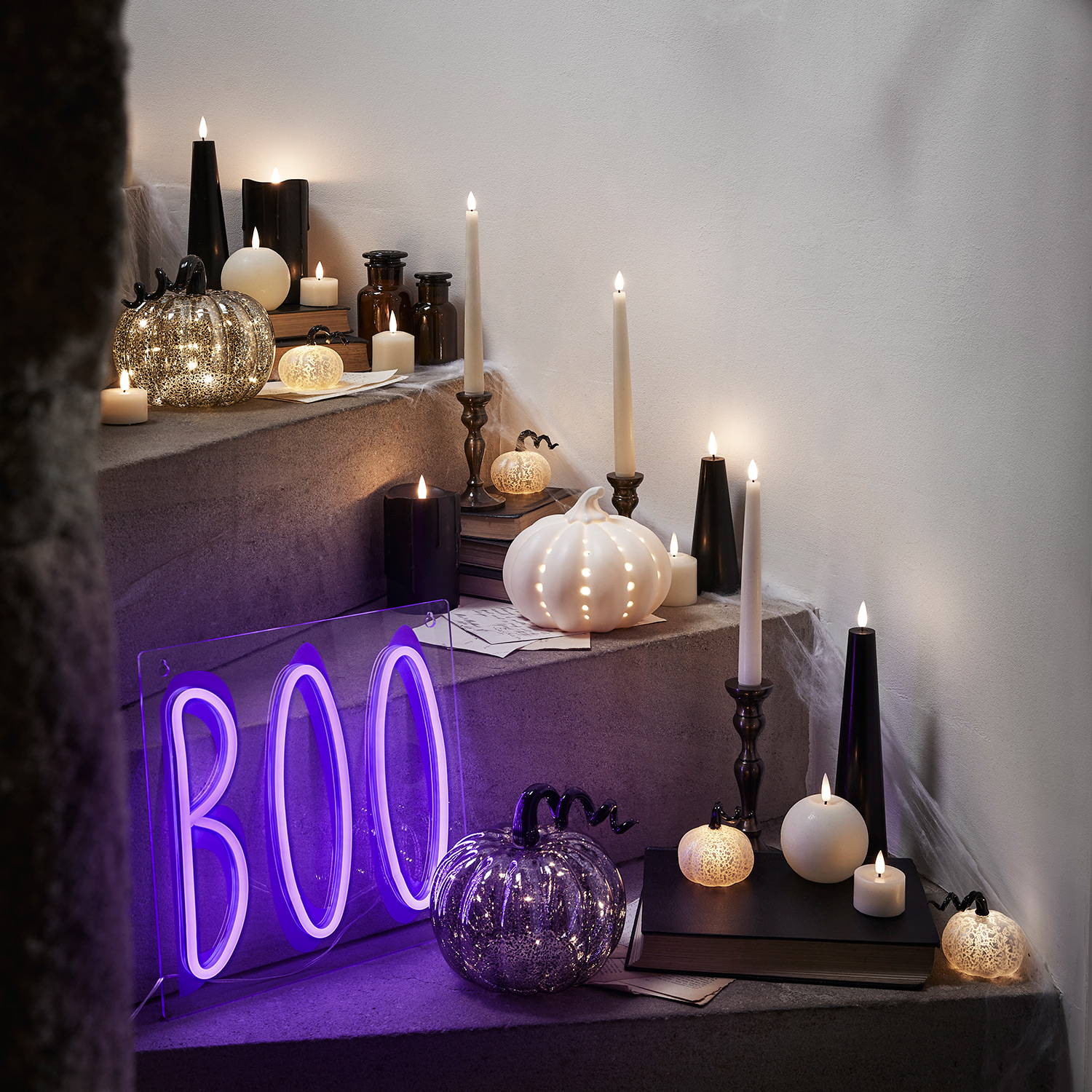 A staircase decorated in Halloween products such as neon wall lights, black candles and mini pumpkin lights.