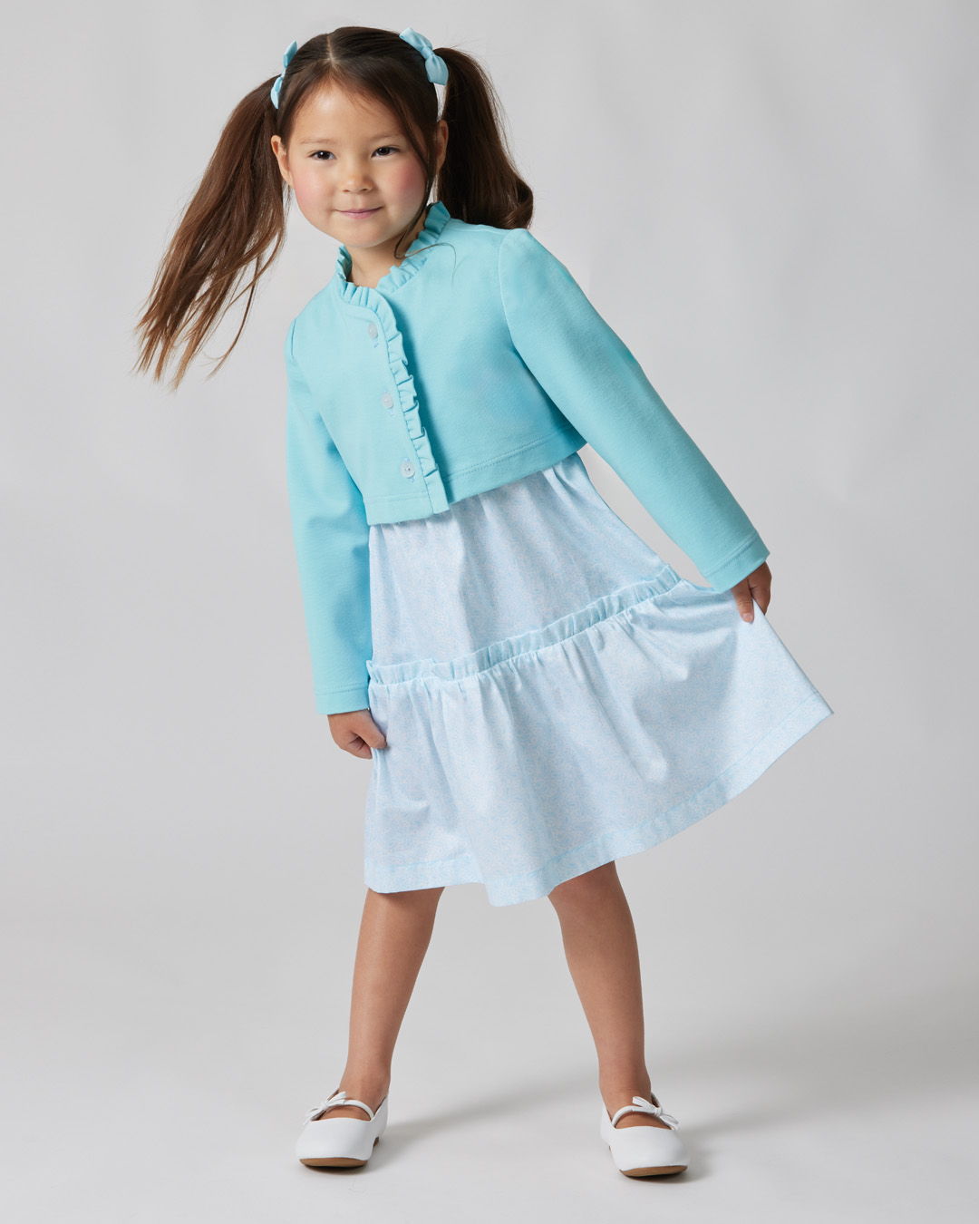 Young girl in a light blue outfit with a cropped jacket and dress.
