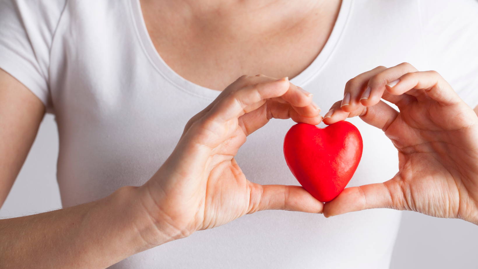 person. holding a red heart over their chest 