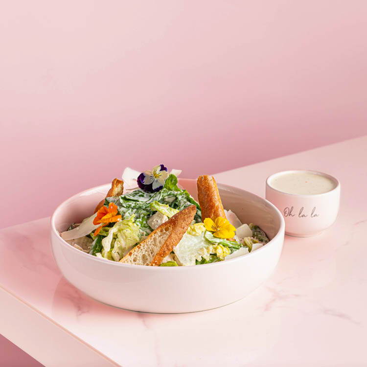 Chicken Caeser salad with foccacia bread croutons on pink background