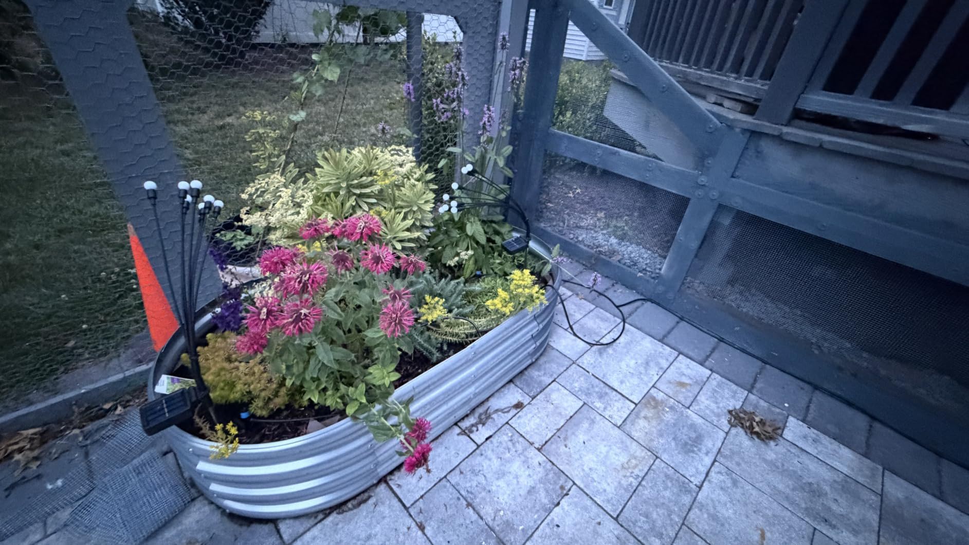 A metal planter filled with colorful flowers on a patio.
