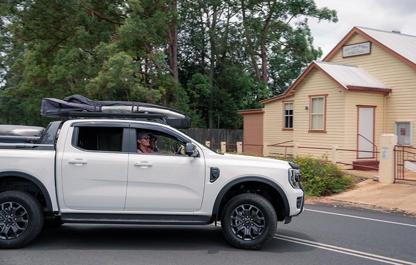 A ute with RuggedLine and Surfboards in front of a building