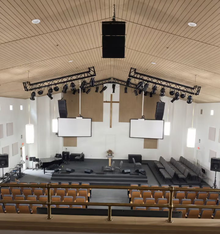 Interior of a modern church with a stage, seating, and lighting.
