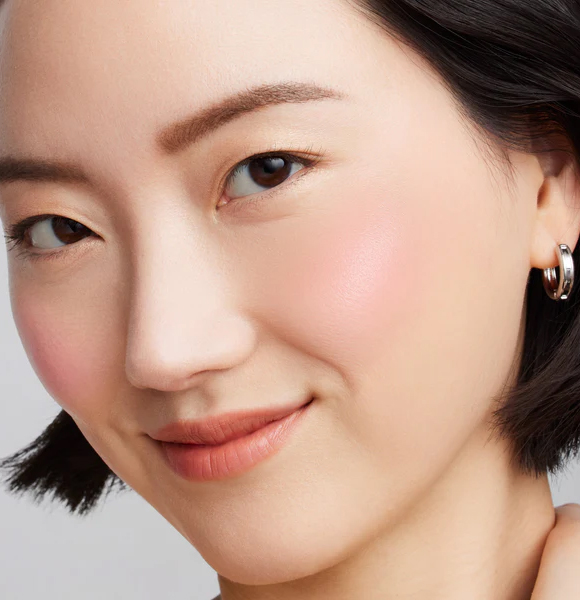 Close-up of a woman smiling with soft makeup and short dark hair.