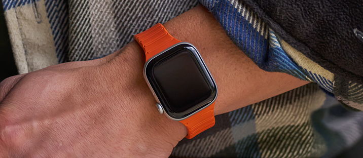 A close-up of a wrist wearing an orange smartwatch.