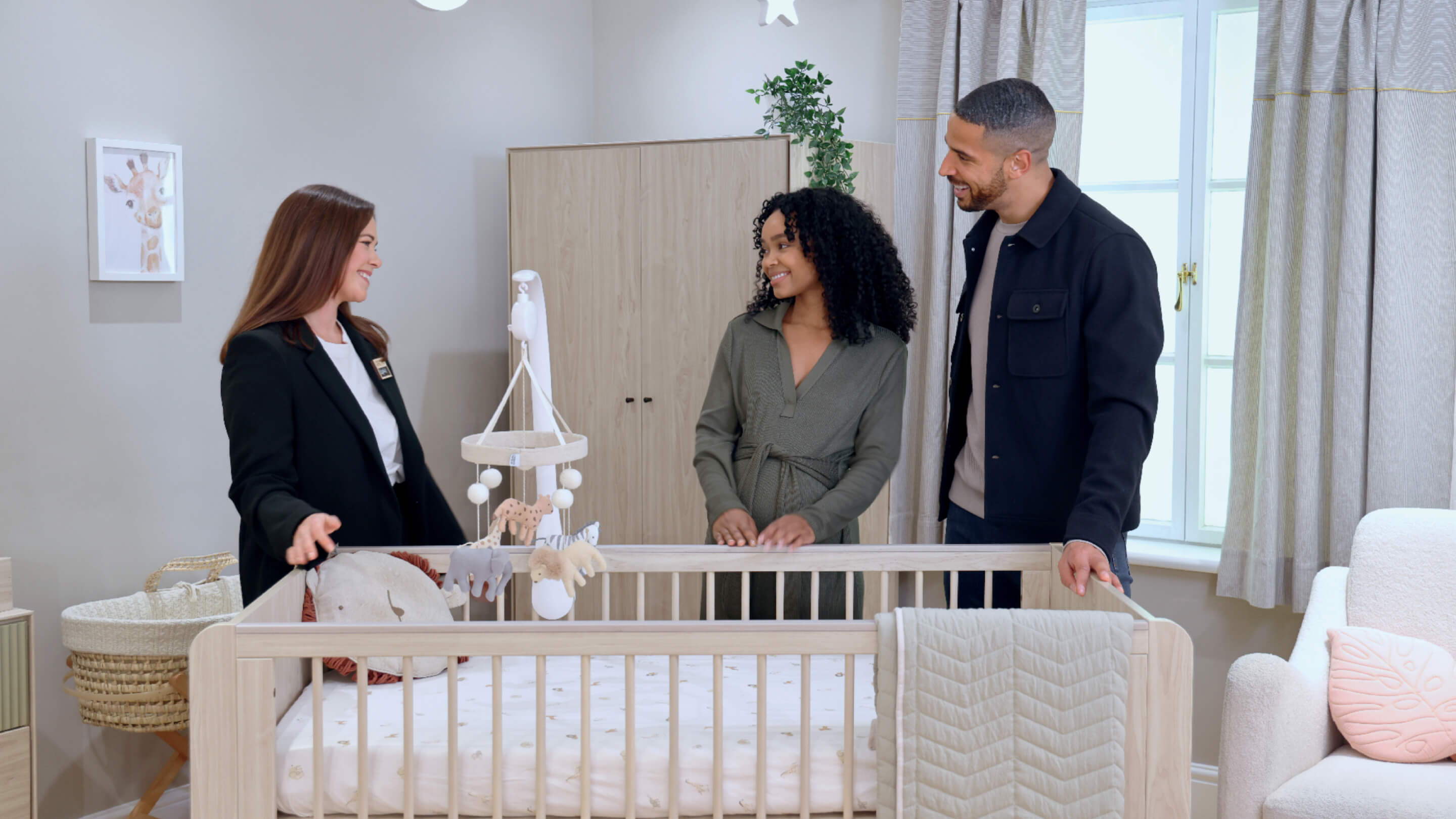 Three people discussing a baby crib in a bright nursery.