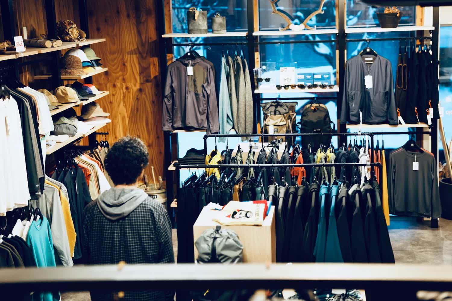 Person browsing clothing in a retail store with various garments displayed.