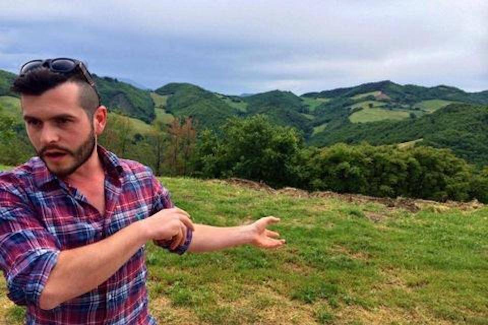 Emilio gestures at mountain grazing land in Le Marche