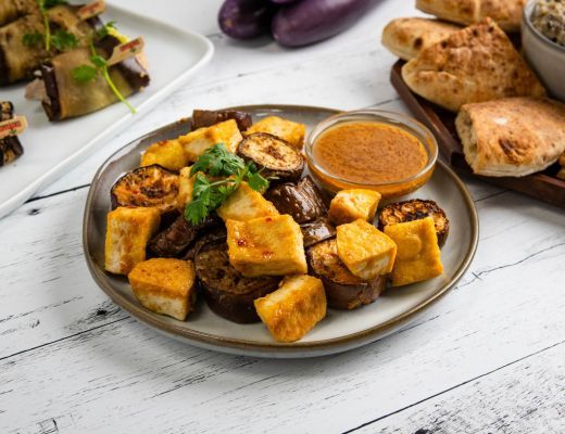 Plate of grilled vegetables and tofu with dipping sauce and flatbreads.