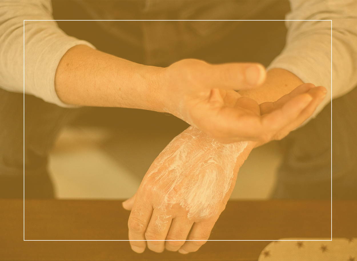 Man gently rubbing moisturizing cream into the backs of his hands to soothe his skin allergies