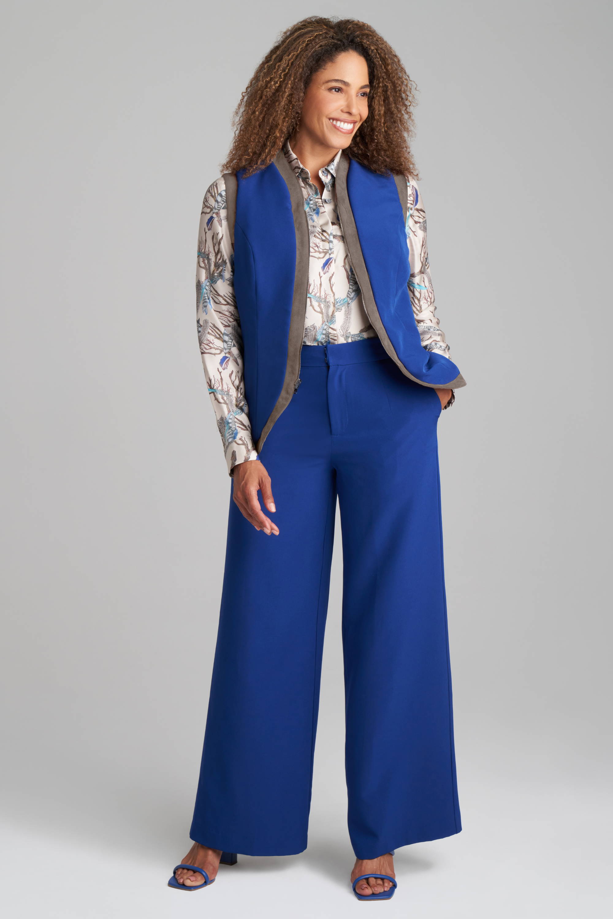 Woman wearing blue vest with feather printed silk shirt with blue pants by Ala von Auersperg