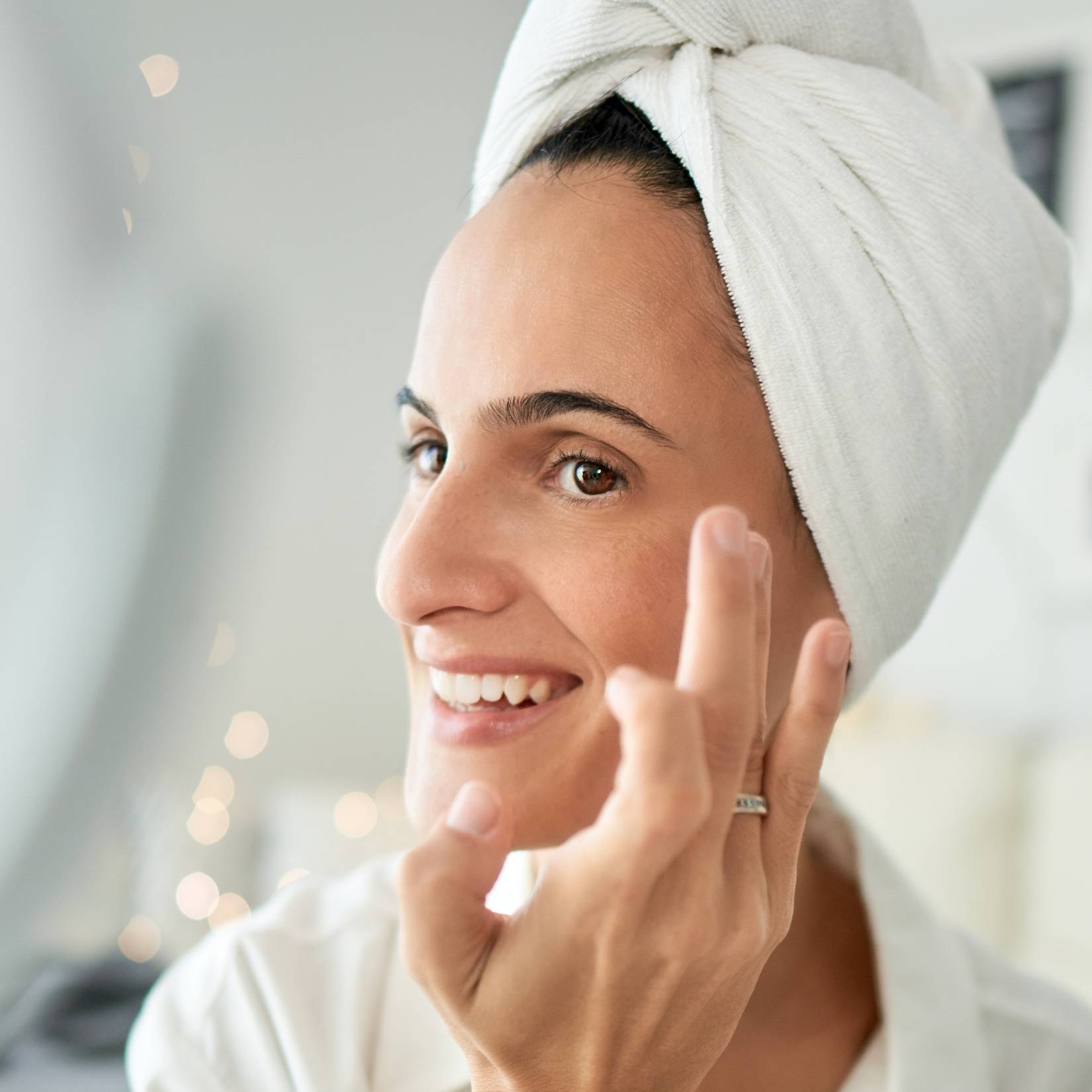 Woman applying skincare to face and smiling