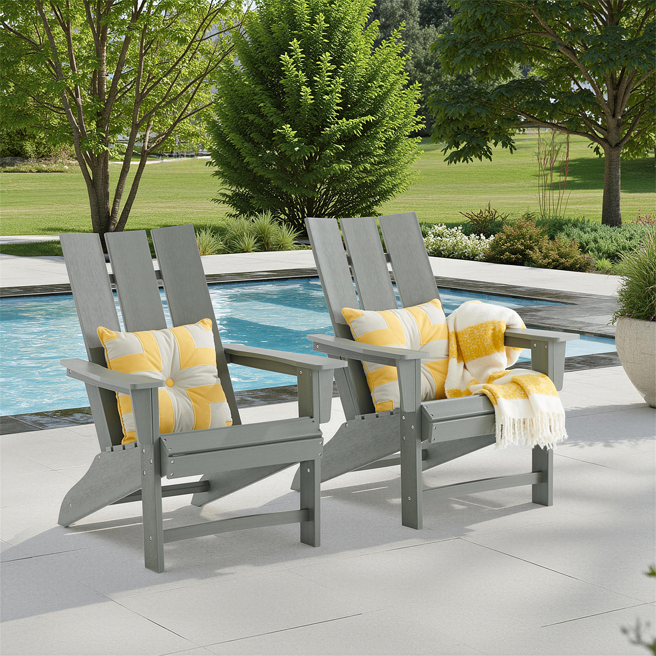 Two gray Adirondack chairs by a pool, with yellow pillows and a blanket.