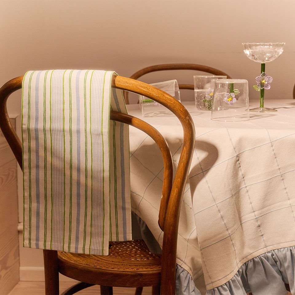 A wooden chair with a striped towel draped over it beside a table.