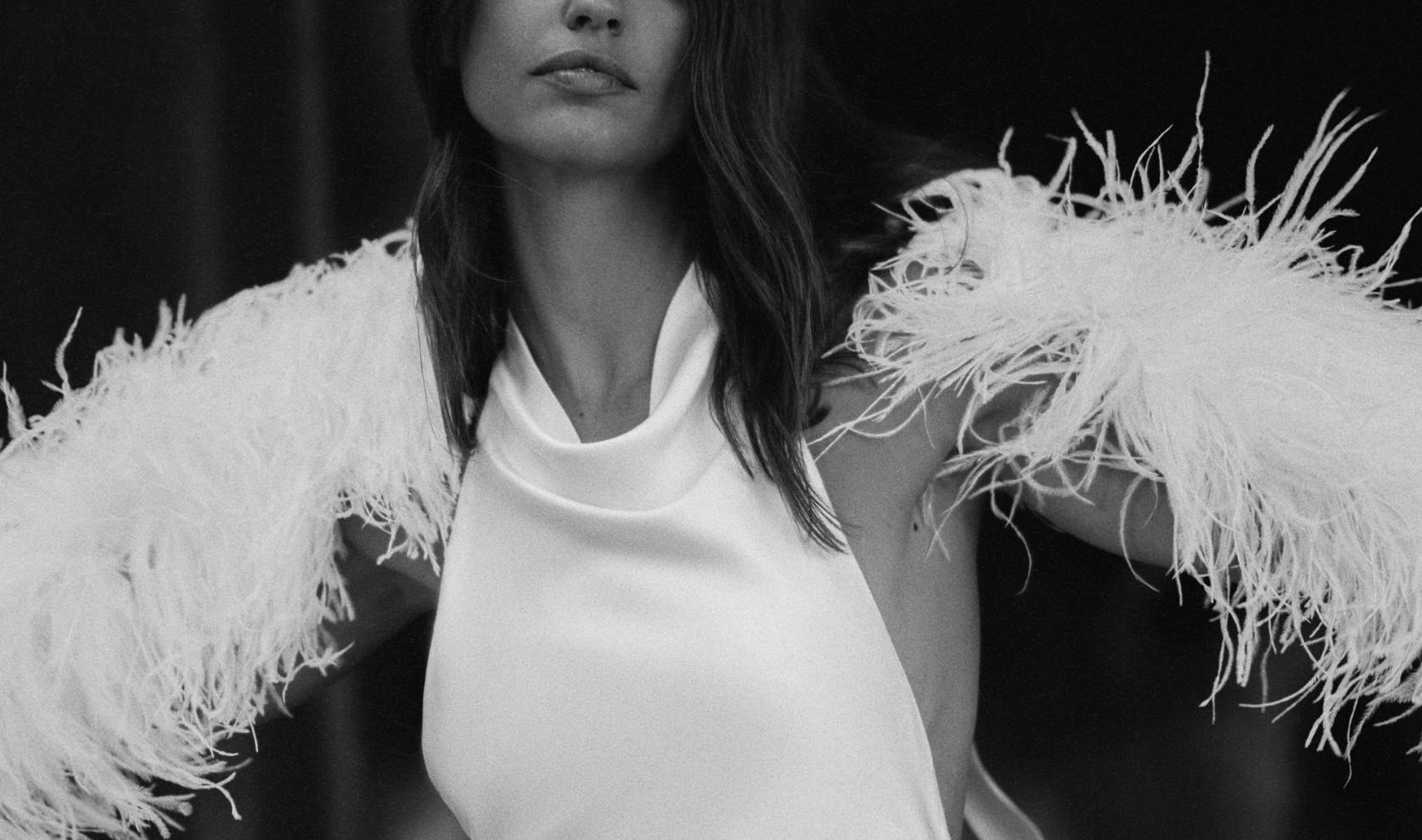 Black and white image of white feather duster on models shoulders