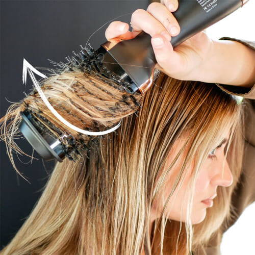 woman achieving a sleek style with blow brush